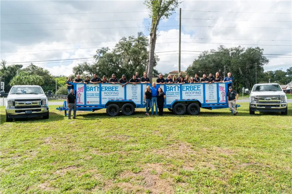 Batterbee Roofing team gathered around branded roofing trailers and service trucks