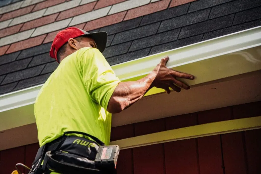 Contractor installing a seamless gutter along a residential roofline