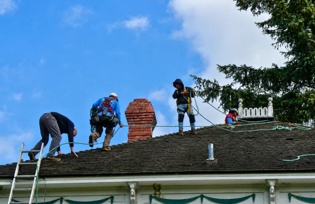 Elite Roofing & Remodel roofing crew performing residential roof replacement and shingle installation on steep slope roof￼